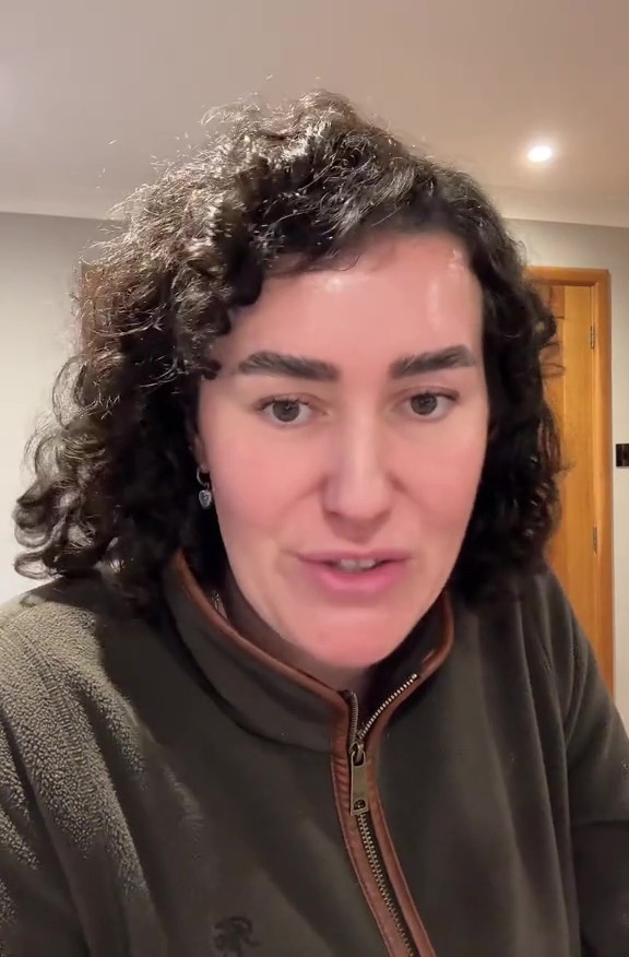 A woman with dark curly hair and a green fleece jacket speaking to the camera.