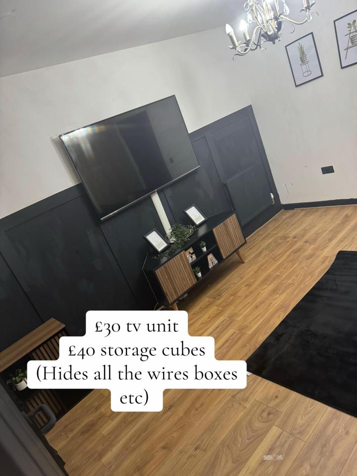 A living room with a black and wood TV unit below a wall-mounted TV, on a wall with black paneling on the bottom and white paint on top. The TV unit and storage cubes cost £30 and £40 respectively.
