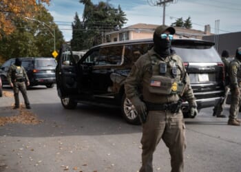 Federal agents stand guard as they are confronted by residents after making a stop while driving in a caravan through the Brighton Park neighborhood on Nov. 6, 2025, in Chicago, Illinois.