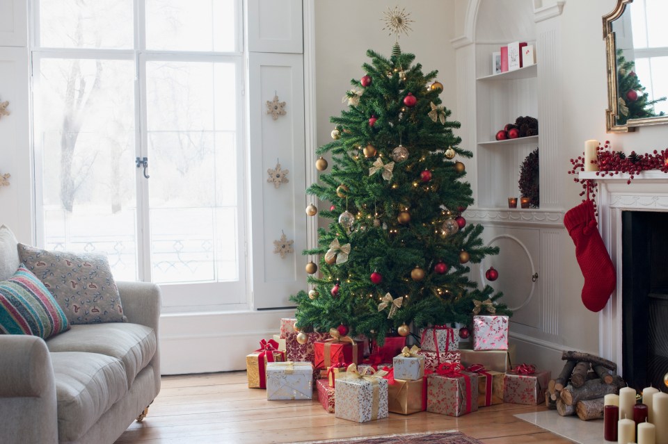 Christmas tree surrounded with gifts in a living room.