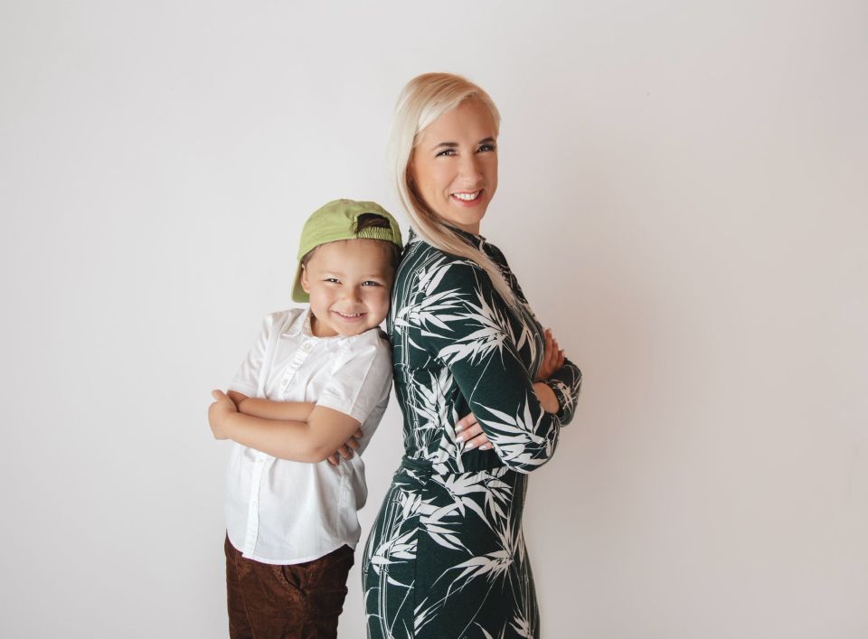 A woman and a young child standing back-to-back, smiling at the camera.