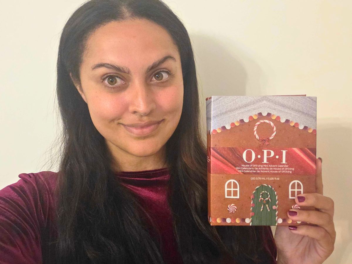 A woman holding an O.P.I. nail polish advent calendar shaped like a gingerbread house.