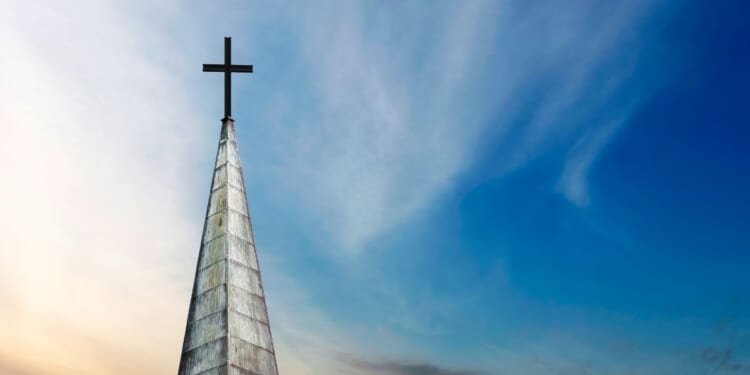 A cross and a church steeple stand still.