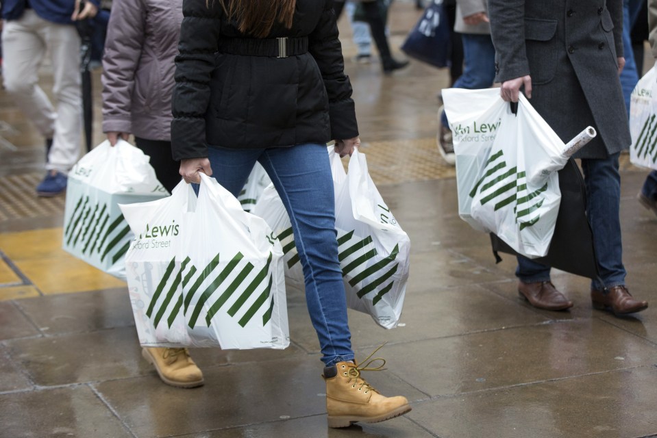 People on Oxford Street carrying white John Lewis shopping bags.