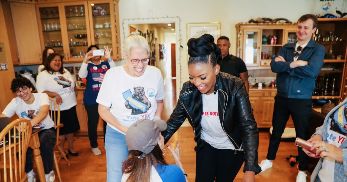 Stephanie Miller greets Texas Democratic Rep. Jasmine Crockett’s feet at an event.