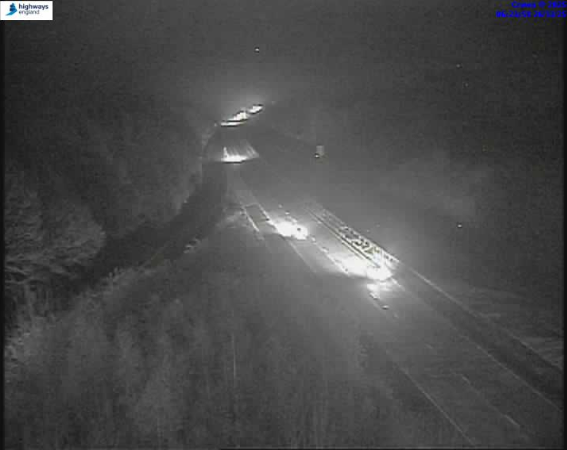 Nighttime traffic camera view of a highway with car headlights visible.
