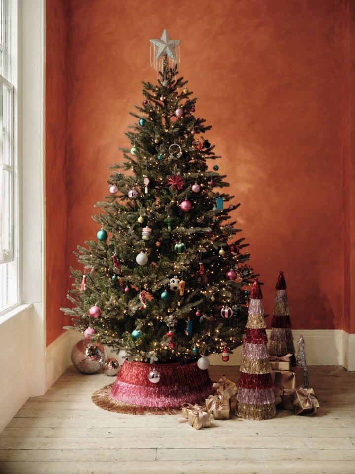 A Marks and Spencer Christmas tree decorated with ornaments, lights, and a star on top.