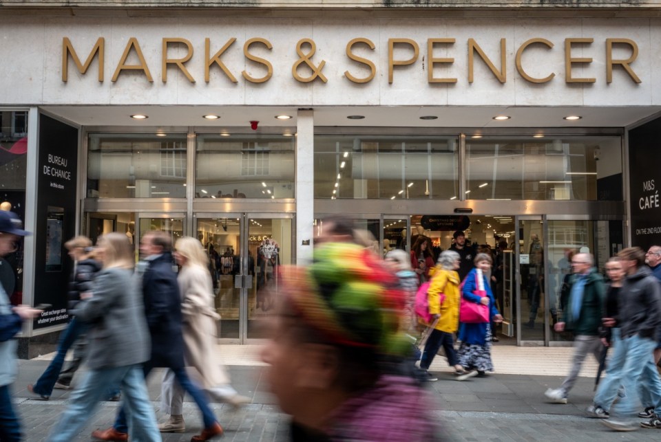 People walking past a Marks & Spencer store entrance.