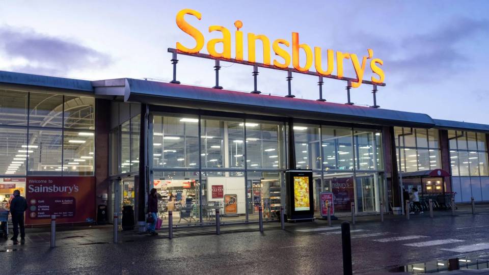 The illuminated Sainsbury's sign on the front of a supermarket.