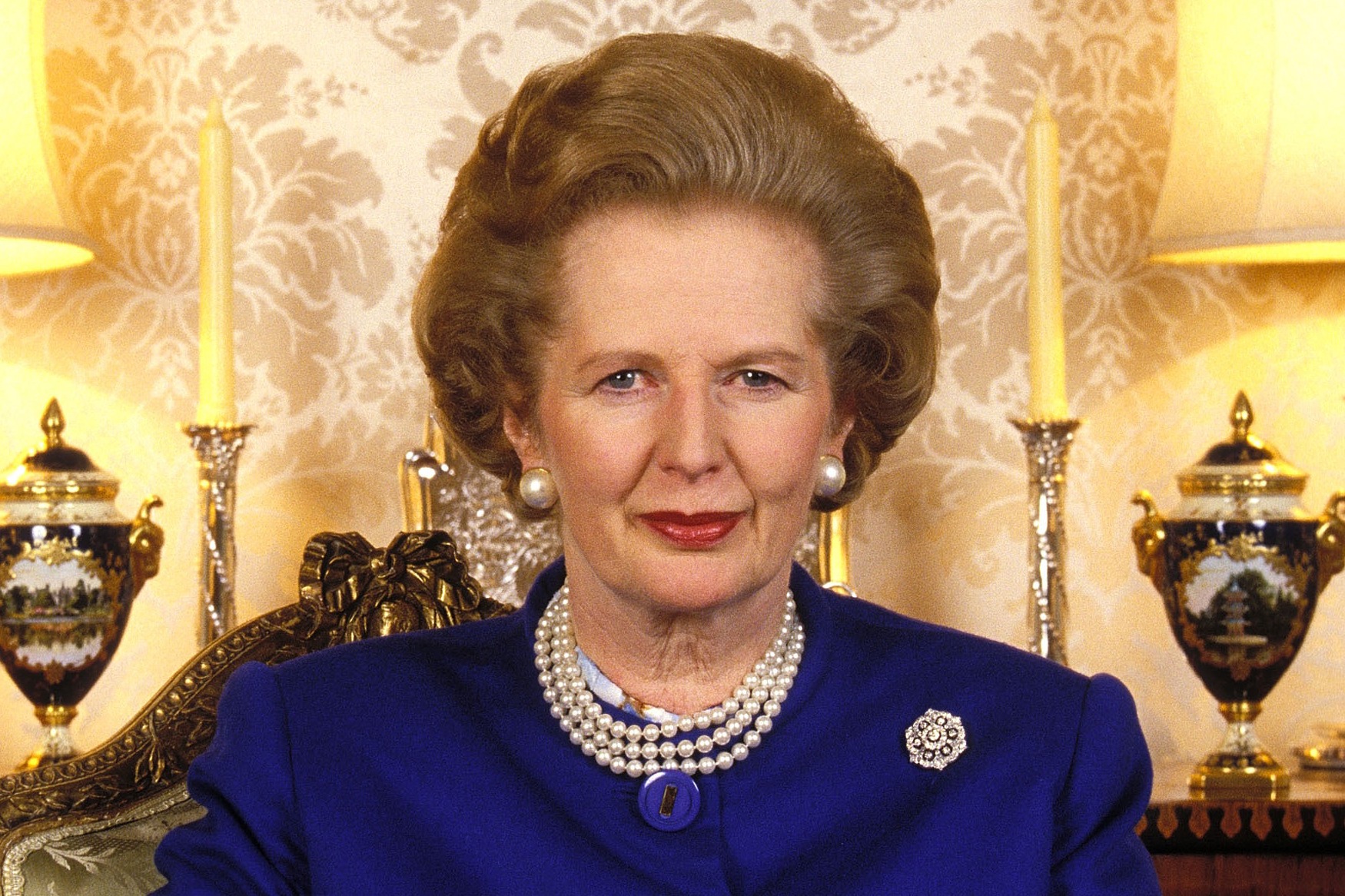 British Prime Minister Margaret Thatcher wearing a blue suit and pearl necklace.