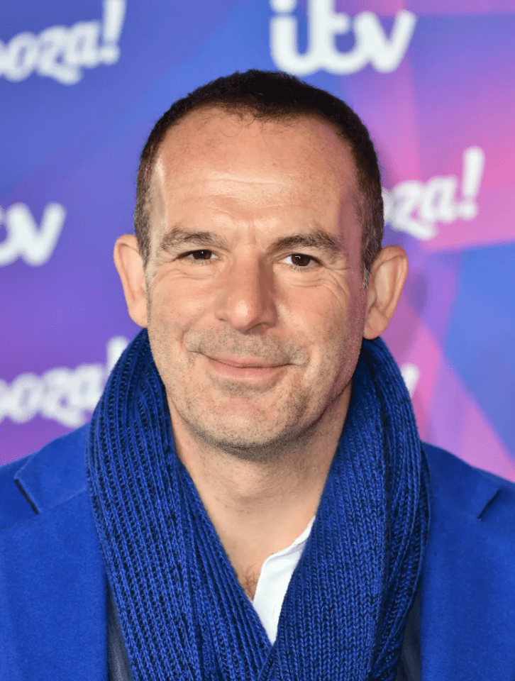 A man in a blue jacket and blue knitted scarf smiles.