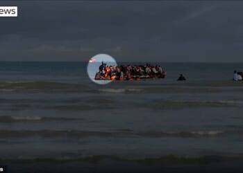 A suspected people smuggler was caught on video pretending to fall off a small boat to evade suspicion from French police