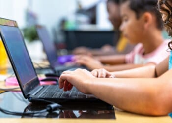 Elementary students work on computers in a computer lab.