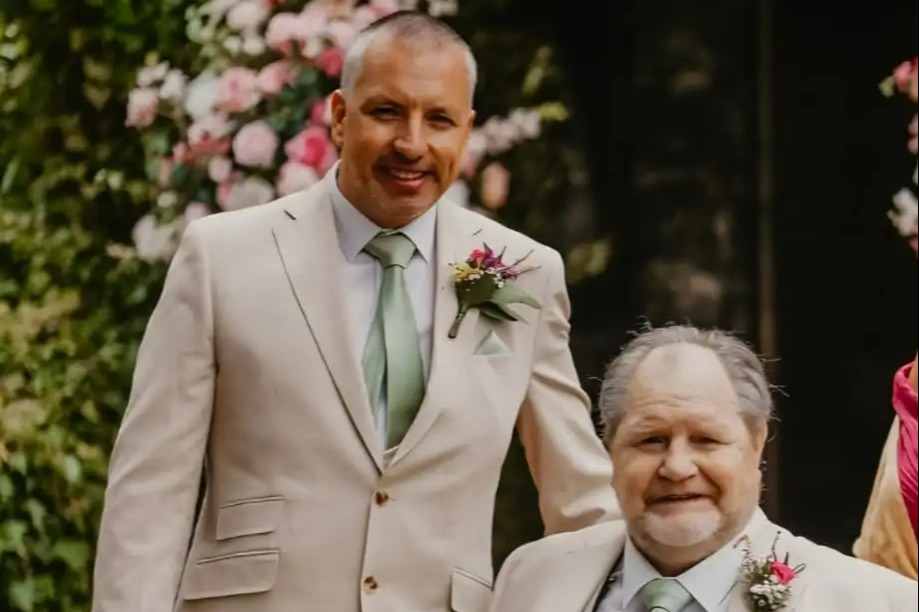 Robin Emerson and dad smiling, both dressed in suits, with dad in a wheelchair.