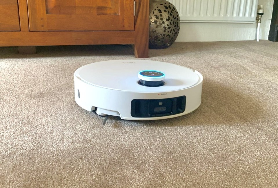 A white robot vacuum cleaner on a beige carpet.