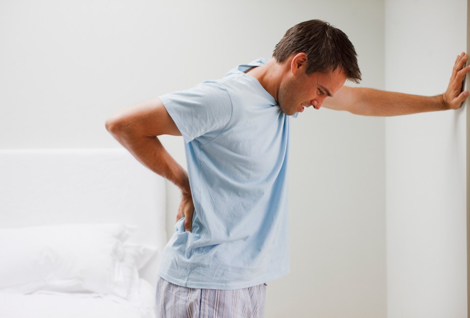 Man with backache leaning against wall