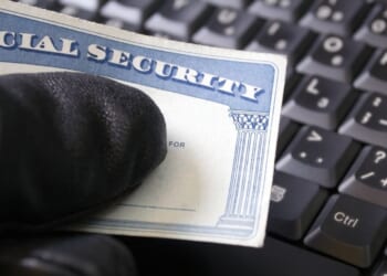 A man's hand holding a Social Security card.