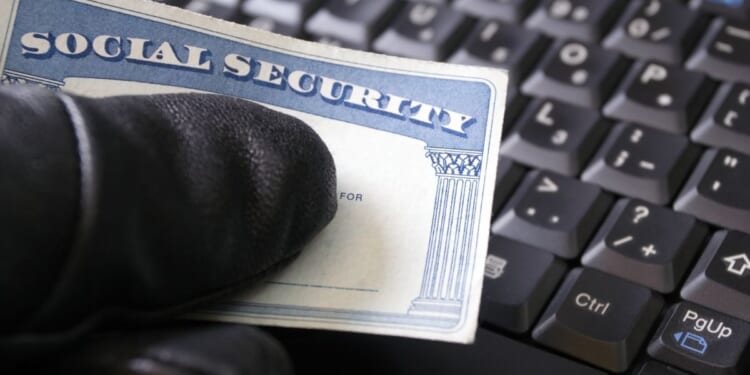 A man's hand holding a Social Security card.