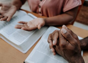 A couple prays together in a stock photograph.
