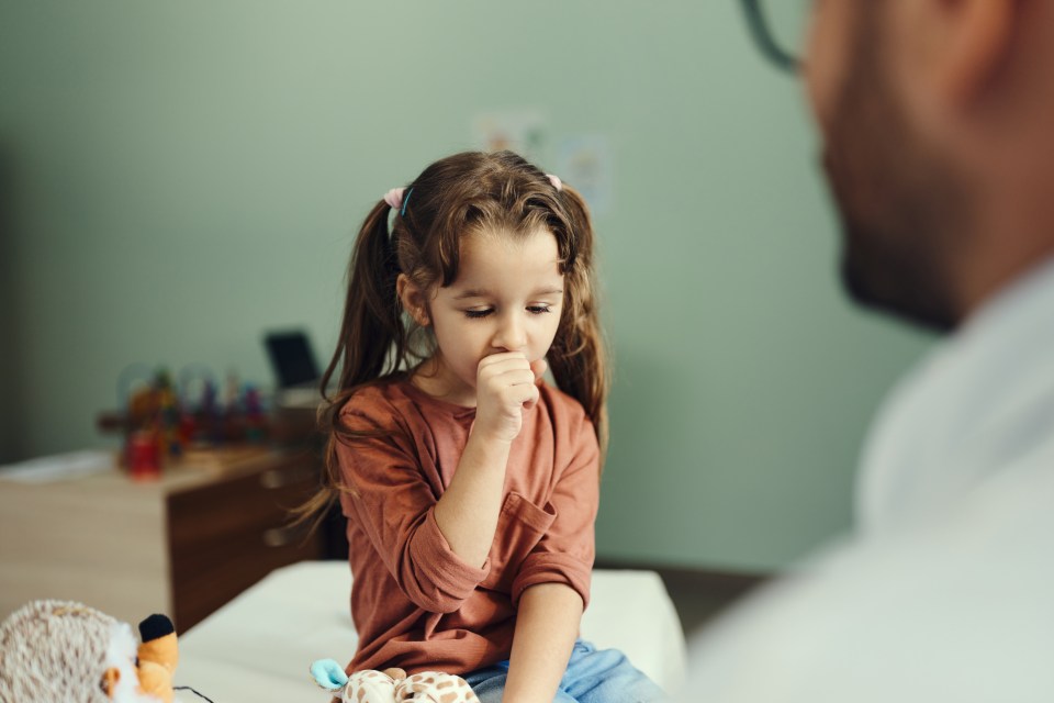 Little girl coughing during a medical exam with her pediatrician.