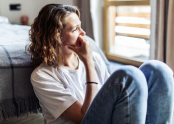 A young woman sits alone.