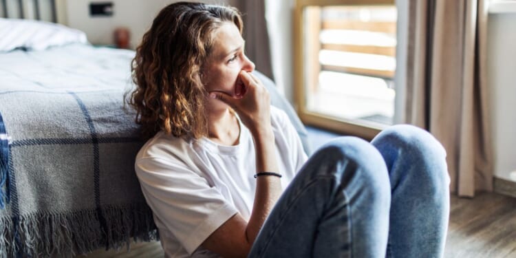 A young woman sits alone.