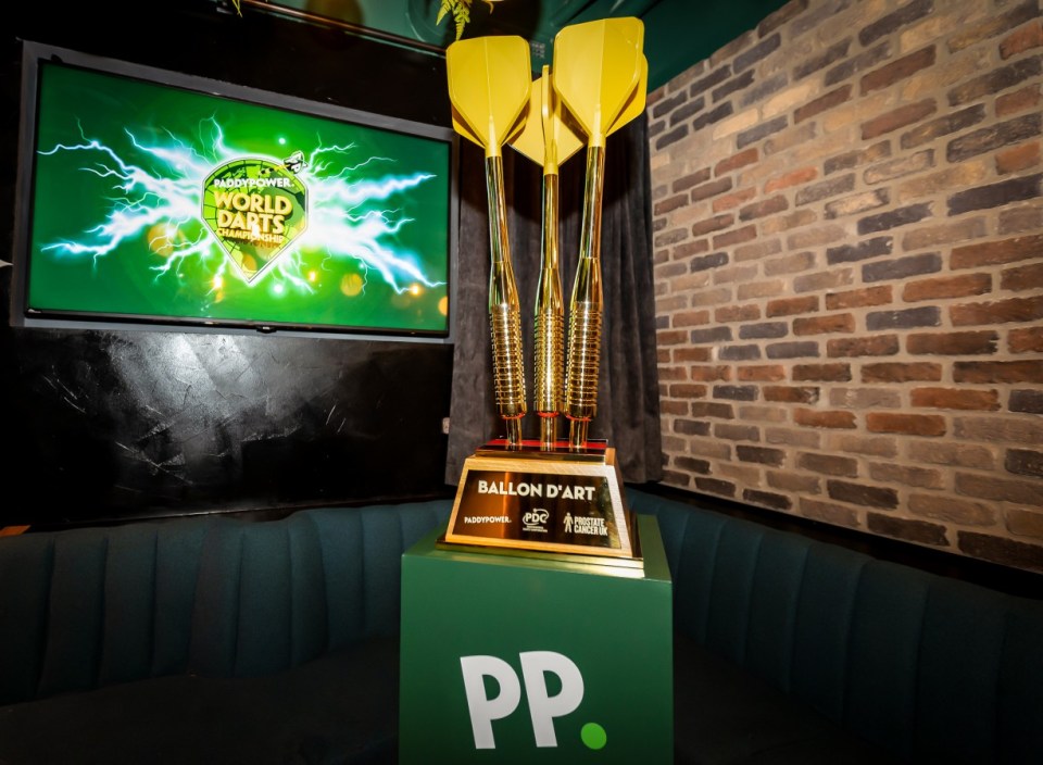 Paddy Power darts images., ,  PLEASE FIND LINK TO MP4 CLIP REVEALING THE BALLON DART TO SOME LESS THAN, IMPRESSED CURRENT DARTS PLAYERS CAN BE FOUND HERE: https://we.tl/t-FCAgvqgV1h,  PROSTATE CANCER UK CHIEF EXECUTIVE LAURA KERBY, AND PDC CHIEF EXEC MATT, PORTER ARE AVAILABLE FOR INTERVIEW THROUGHOUT THE TOURNAMENT (see, editors note below for contact details), , (London, 4/12/23) A brand new trophy has been revealed ahead of the Paddy Power World, Darts Championship at the Alexandra Palace  the Ballon dArt., The prestigious Sid Waddell Trophy will of course remain the supreme accolade for the, tournaments eventual champion, but the new World Championship sponsors have created, an additional mammoth trophy for the player who scores the most 180s during the, showpiece event., The new award, probably the biggest darts trophy on the planet, is the latest addition to, THE BIG 180 Campaign, which will see Paddy Power donate £1,000 to Prostate Cancer UK, for every maximum scored during the 2023/24 World Darts Championship.