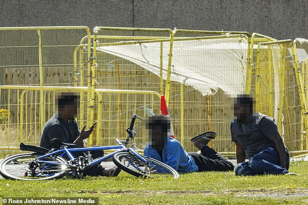 Police have launched a probe after a man was attacked at a hotel that has been used to house asylum seekers in Aberdeen. Pictured: Men sit on the ground at one of the migrant hotels in Aberdeen