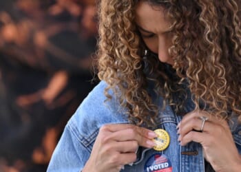 A young woman attaches a pin to her jacket after voting at a mobile outdoor vote center at SoFi Stadium in Los Angeles, California, on Election Day, Nov. 5, 2024.