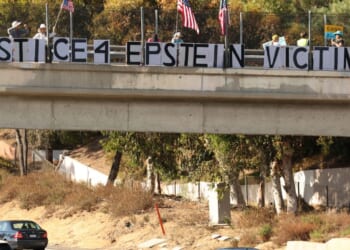 People hold American flags and signs reading "Justice 4 Epstein Victims" on a freeway overpass in Encinitas, California, on July 31, 2025.