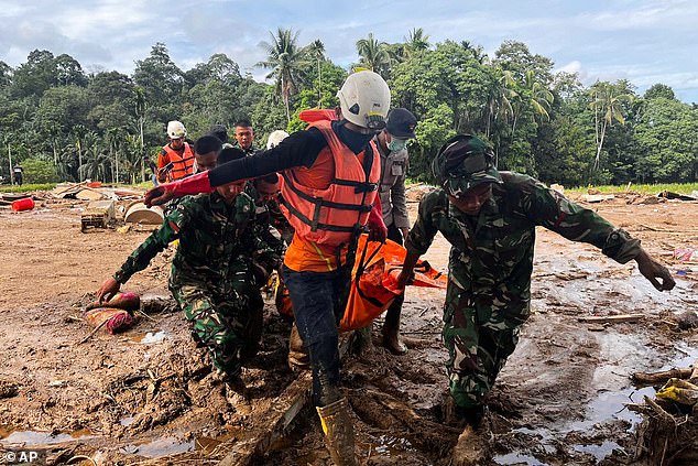 Rescuers carry a person through the flood-devastated region of West Sumatra, Indonesia, on Sunday amid an urgent search for hundreds of missing individuals