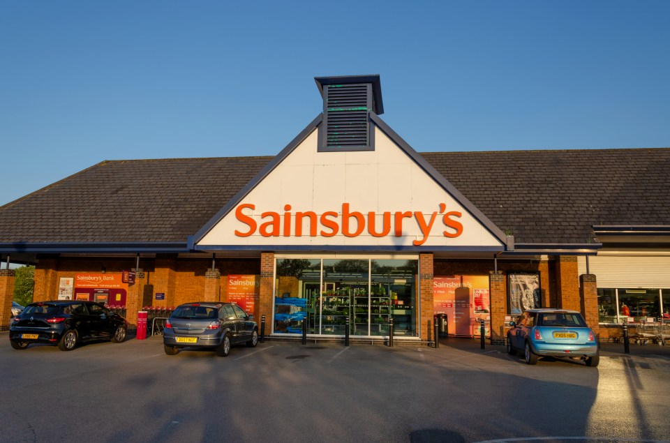 Sainsbury's store in Flint, UK with cars parked in front.