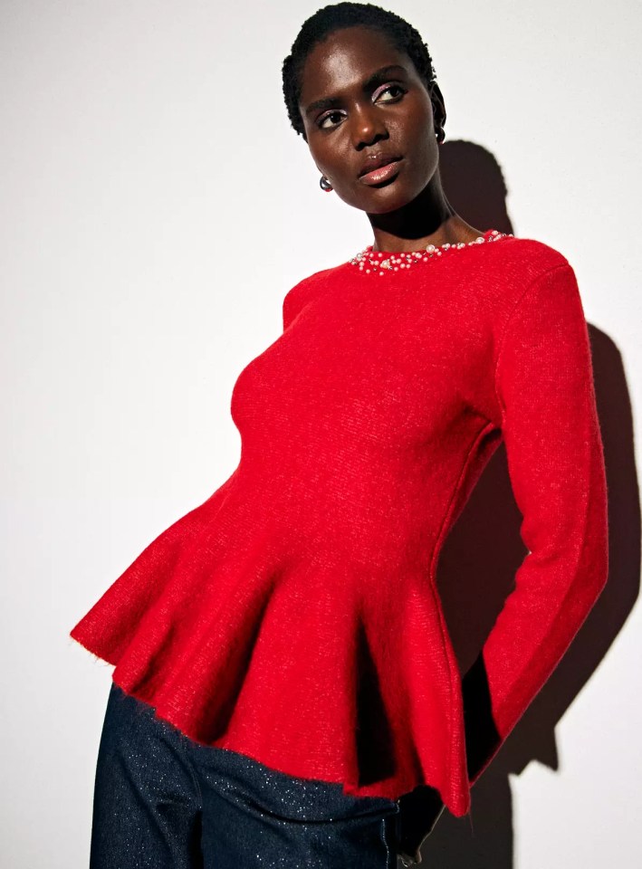 Woman wearing a red peplum top with pearl details on the neckline.