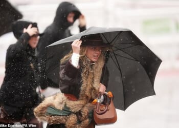 Racegoers battle the rainy conditions during the first day at Cheltenham Racecourse