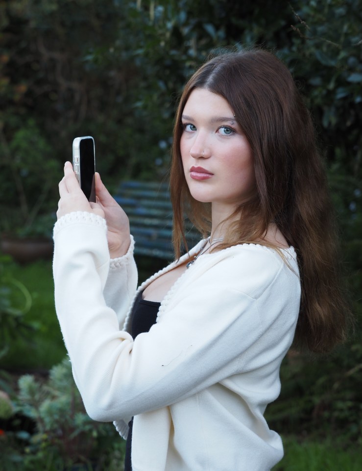 A young woman from Devon, Flossie McShea, holding a smartphone, looking at the viewer.