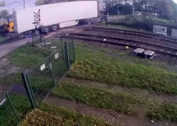 CCTV footage shows the fruit-loaded vehicle bizarrely reverse onto the tracks as the barriers close shut in the village of Meteren, central Netherlands