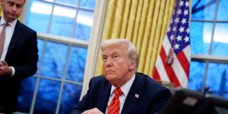 President Donald Trump, accompanied by White House Staff Secretary Will Scharf, appears at the Resolute Desk as he signs a series of executive orders including 25 percent tariffs on steel and aluminum, a pardon for former Illinois Gov.