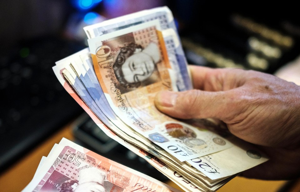 Hands counting British pound banknotes.