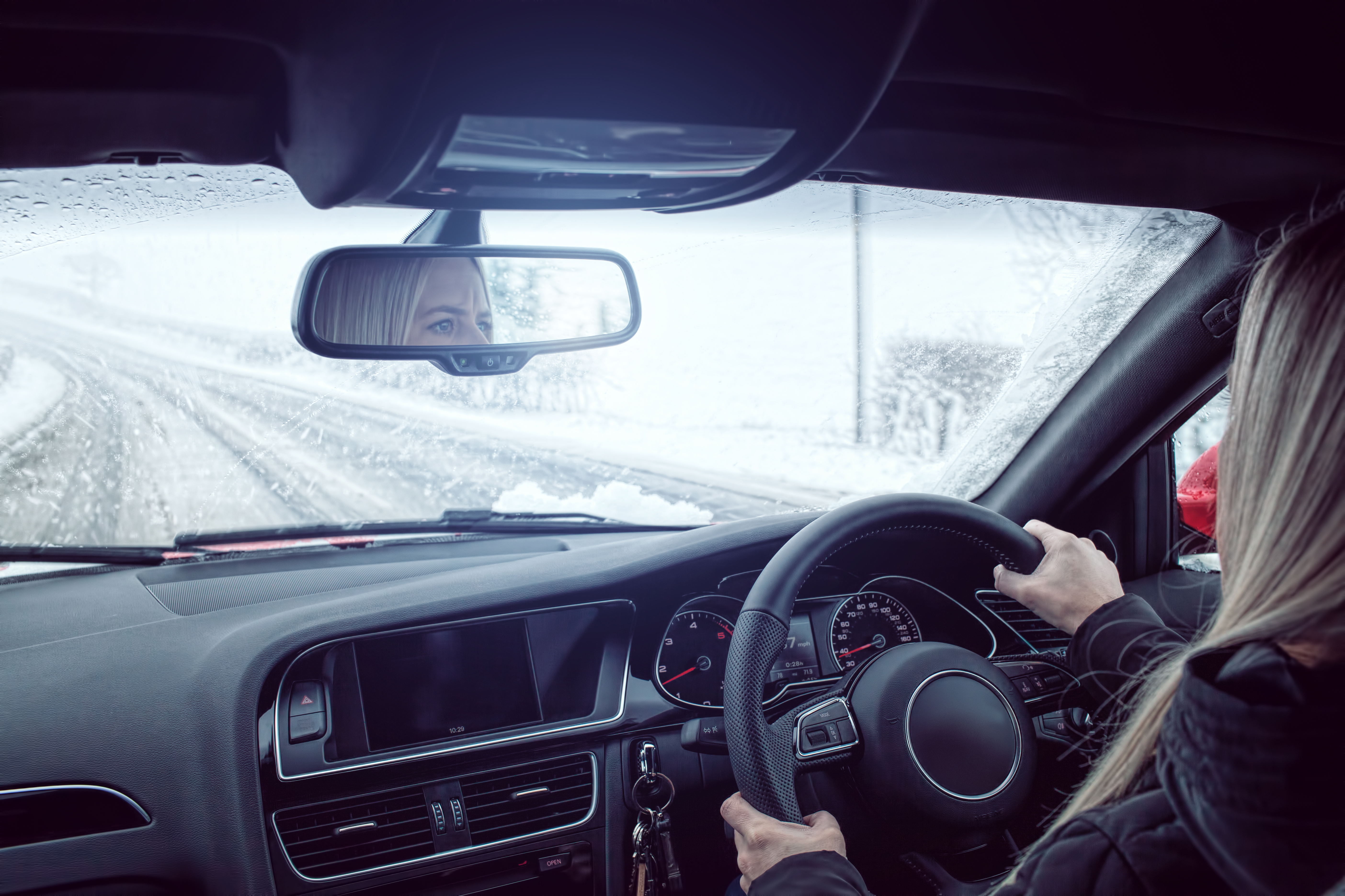 Woman driving a car in snowy conditions.