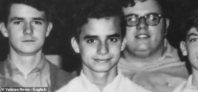 Several years later, another photo captures him as a teenager, standing among friends with a shy, close-lipped smile