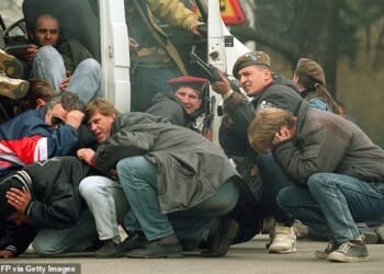 In 1992, a Bosnian soldier returns fire in Sarajevo as he and civilians come under fire from Serbian snipers