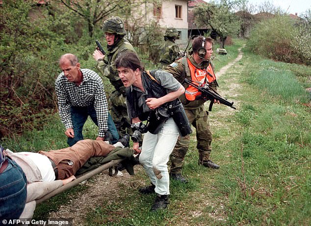 Romanian freelance photographer Vadim Ghirda (C) and locals carry a dead Bosnian Muslim as Norwegian and Swedish IFOR soldiers return fire at Bosnian Serb gunmen, 1996