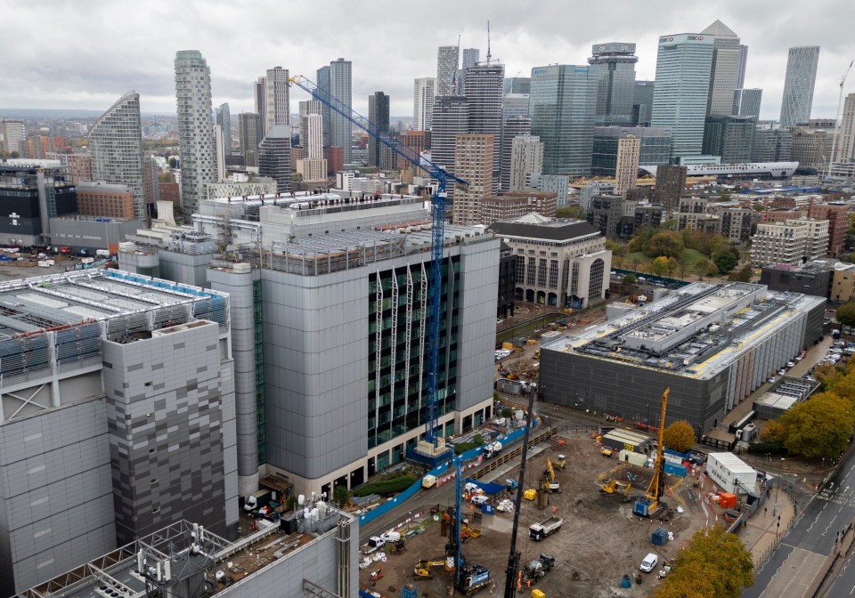 An aerial view of Canary Wharf with cranes, construction sites, and tall buildings.