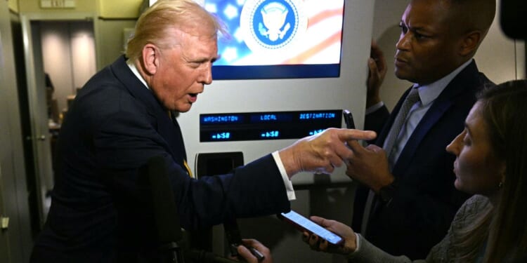 President Donald Trump points as he speaks to reporters Friday aboard Air Force One en route to Palm Beach, Florida.