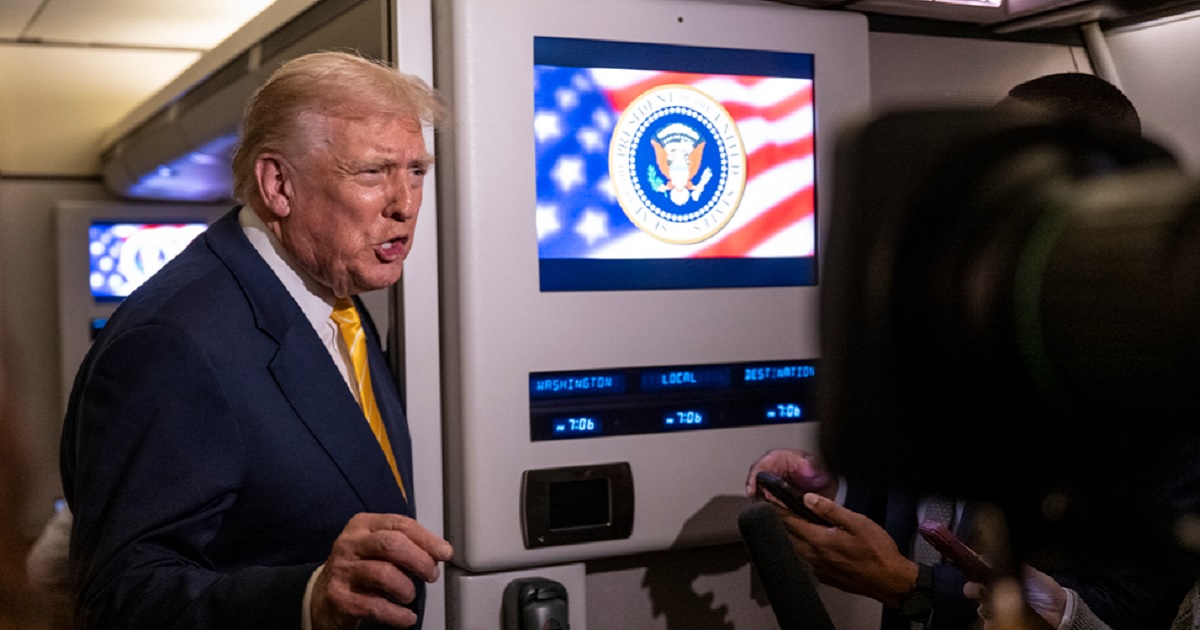 President Donald Trump speaks to reporters aboard Air Force One on Friday while in flight from Washington to West Palm Beach International Airport.