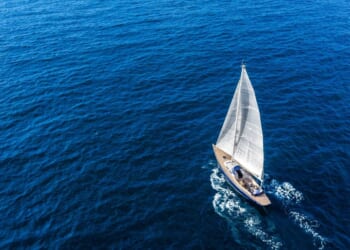 An aerial view of a sail boat floating in the Mediterranean sea.