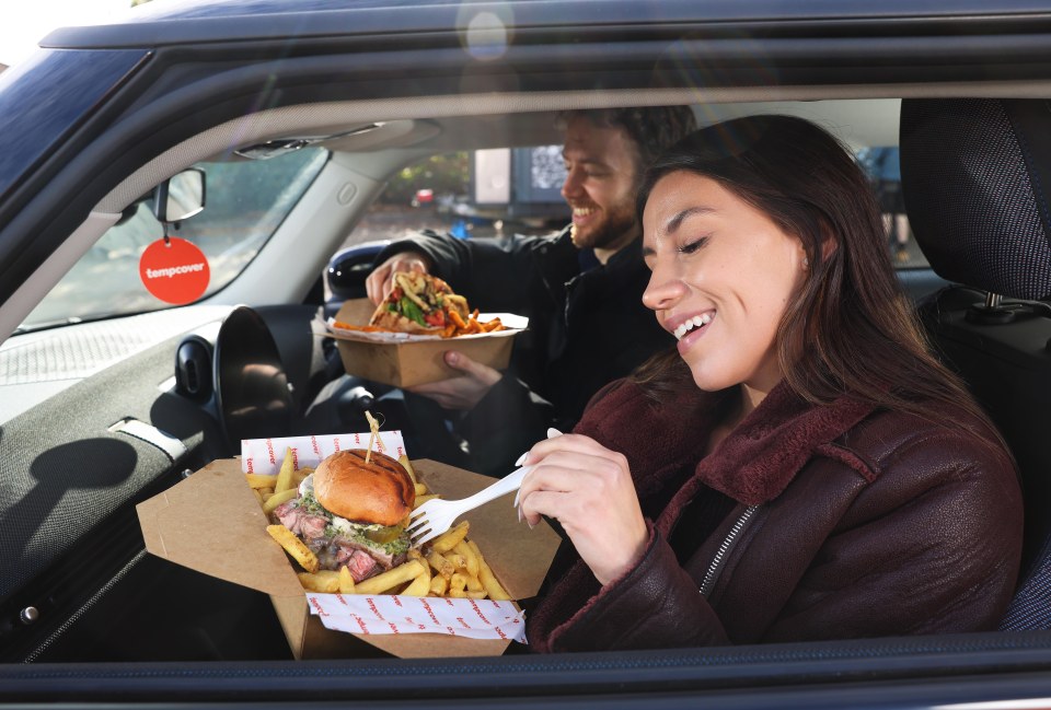 Two people in a car eating food from Tempcover branded packaging.