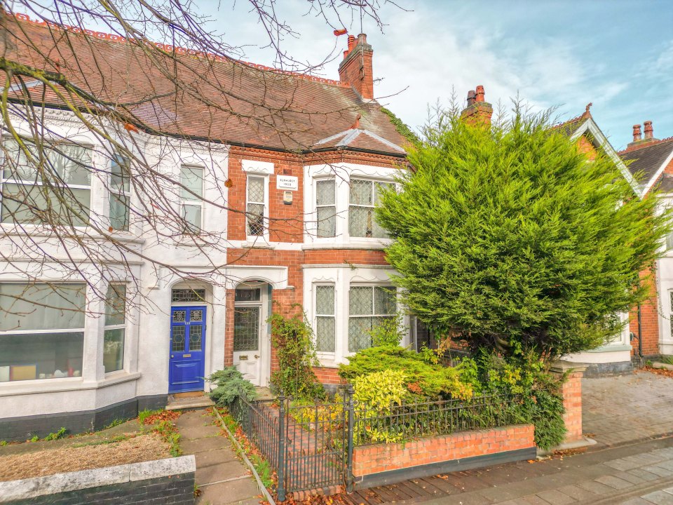 Exterior of a brick and white semi-detached Edwardian house with a blue door.