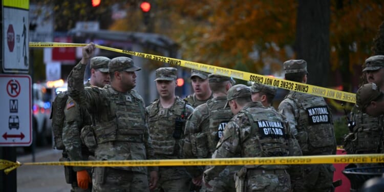 National Guard soldiers stand behind the crime scene tape at a corner in downtown Washington, D.C., on Nov. 26, 2025.