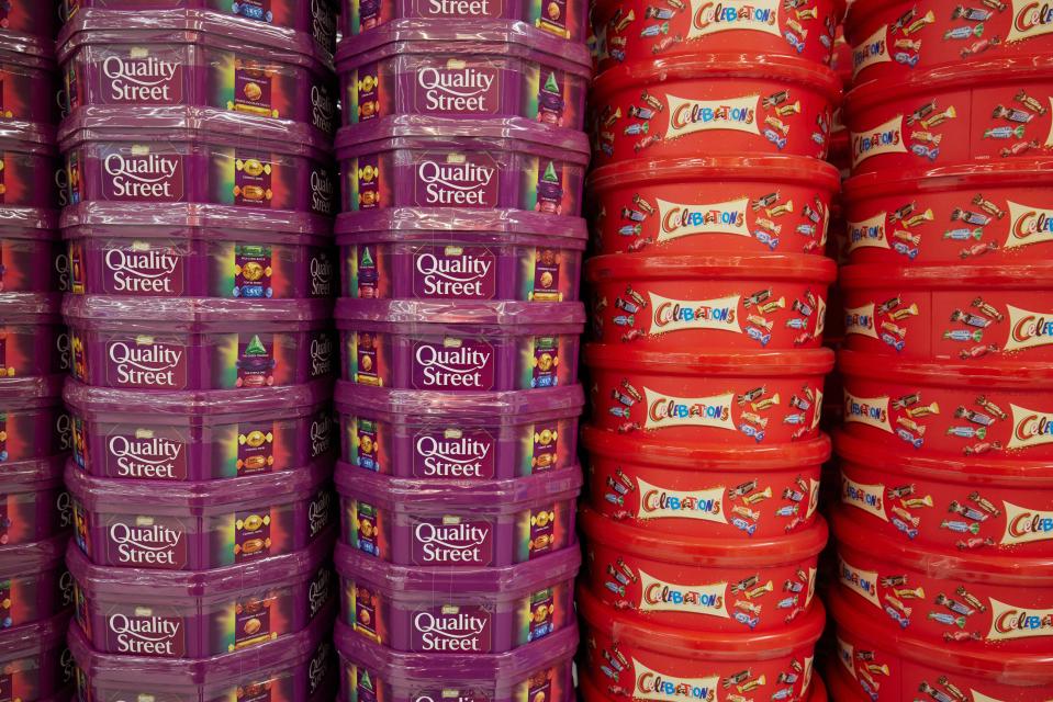 Quality Street and Celebrations plastic tubs stacked up in a shop.